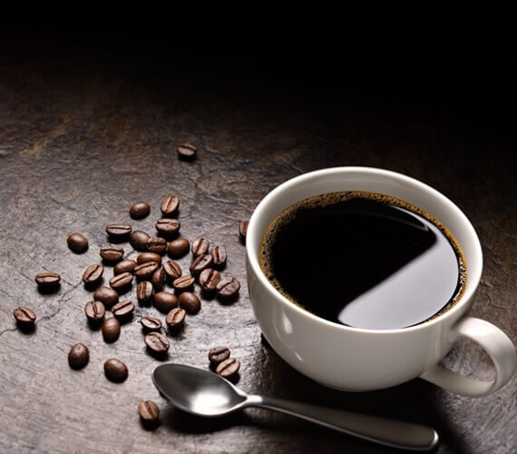 xícara de café ao lado de grãos de café na mesa