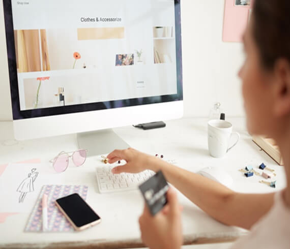 mulher olhando loja online no computador e segurando o cartão de crédito