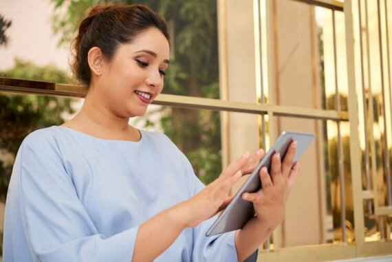 mulher de blusa azul mexendo no tablet