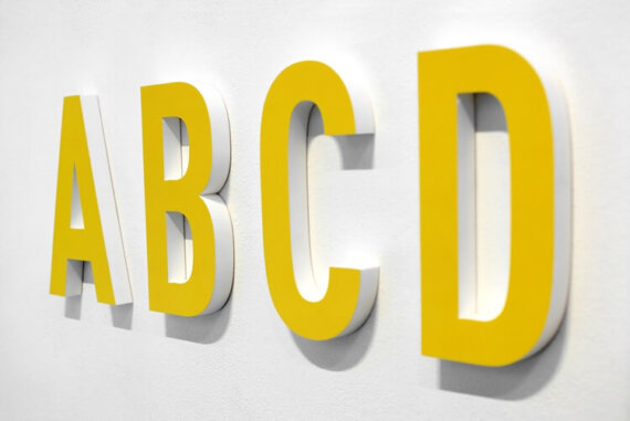 letras A B C D em amarelo colada na parede, simbolizando o blogpost sobre naming de empresas.