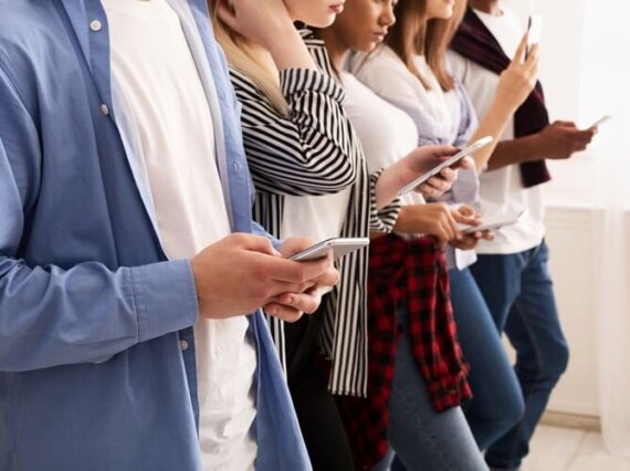 fileira de pessoas lado a lado, segurando o celular, simbolizando o blogpost sobre estratégia de negócios.