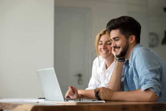 duas pessoas mexendo em um notebook e sorrindo feliz