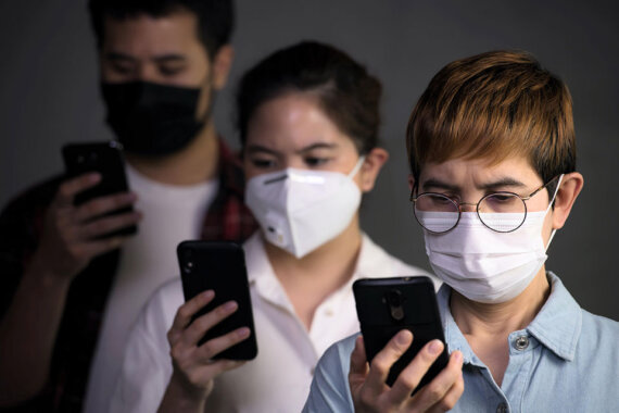 Papel das marcas na pandemia: Pessoas com máscaras cirúrgicas se previnem contra o coronavírus covid-19 enquanto olham nas telas dos seus celulares os posicionamentos das marcas e negócios