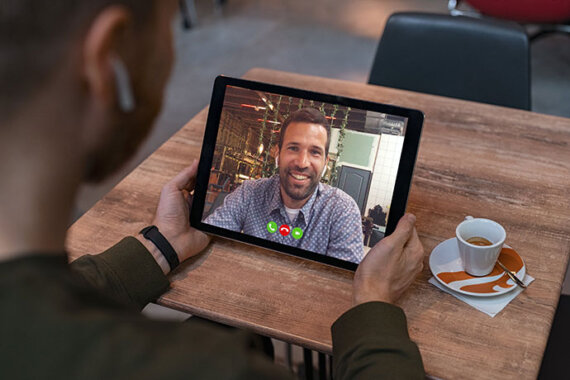 Qual o melhor aplicativo de chat on-line: Homem segurando tablet e conversando por aplicativo com colega