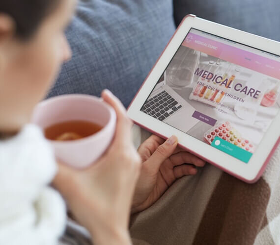 mulher lendo um site de um um hospital e tomando um chá