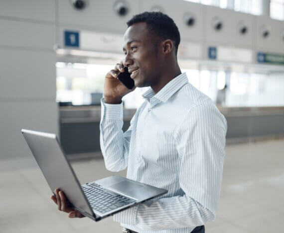 homem sorrindo ao telefone e segurando um computador